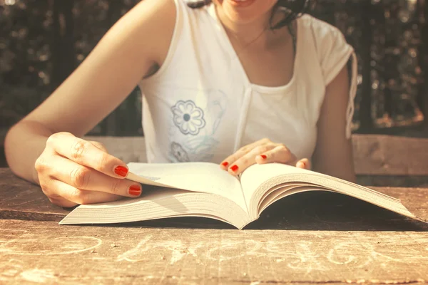 Feminino lendo um livro na mesa no parque — Fotografia de Stock