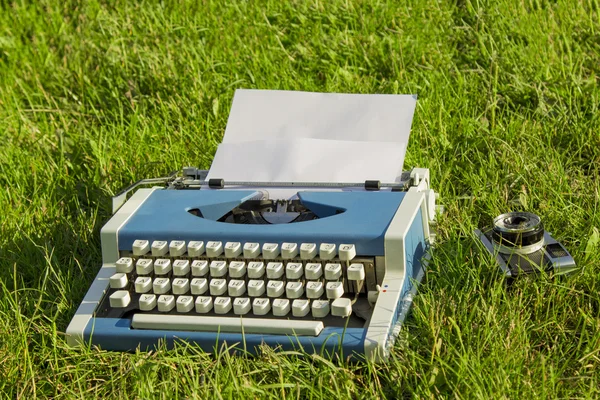 Máquina de escribir y cámara vieja en la hierba — Foto de Stock