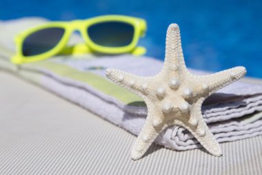 Deniz yıldızı, havlu ve şezlong üzerinde güneş gözlüğü