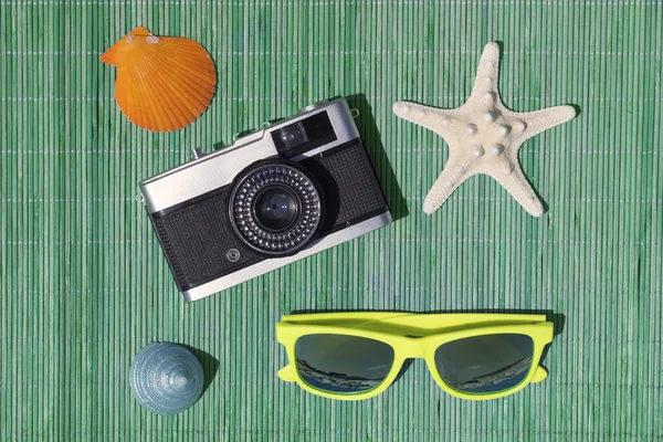 Stella marina, fotocamera retrò, occhiali da sole, lumaca di mare e conchiglia sul tappetino di paglia di bambù — Foto Stock