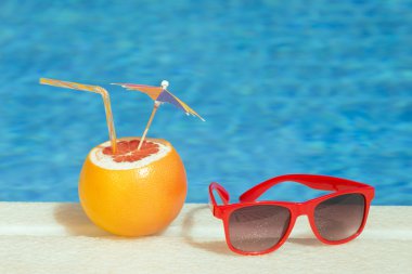 Greyfurt taze meyve suyu içecek ve güneş gözlüğü havuz başı