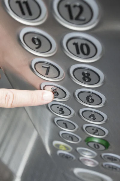 Dedo indicador pressionando o botão do quinto andar no elevador — Fotografia de Stock