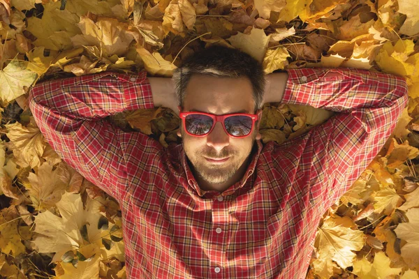 Chico acostado en el suelo y disfrutando de la temporada de otoño — Foto de Stock