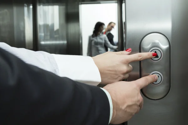 女性と男性の人差し指が別の方向にエレベーターのボタンを押します。鏡の反射. — ストック写真