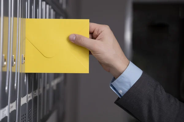 Hand in Hand den gelben Brief in den Briefkasten legen — Stockfoto