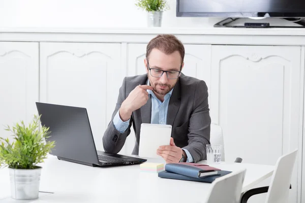 Бизнесмен смотрит на цифровое планшетное устройство на рабочем столе — стоковое фото