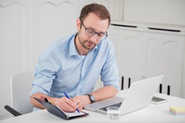 Profesyonel genç erkek ofis masasında oturan ve not yazma    