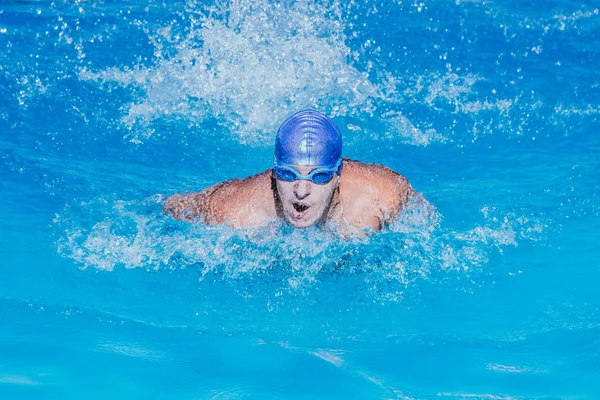 Retrato de un nadador en gorra respirando realizando el golpe de mariposa — Foto de Stock