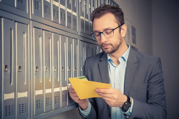 Schöner Mann im Anzug, der neben den Briefkästen Post checkt — Stockfoto