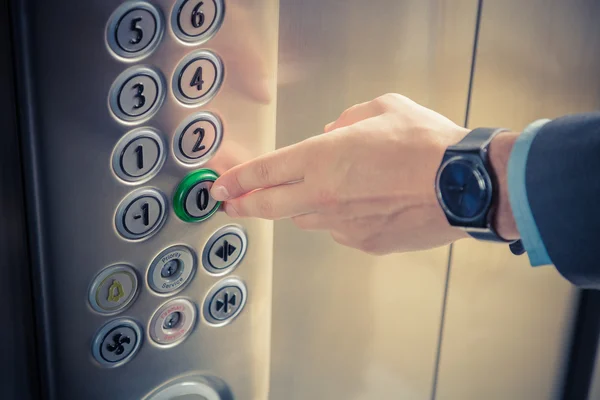 Мужской палец нажимает кнопку нулевого этажа в лифте — стоковое фото