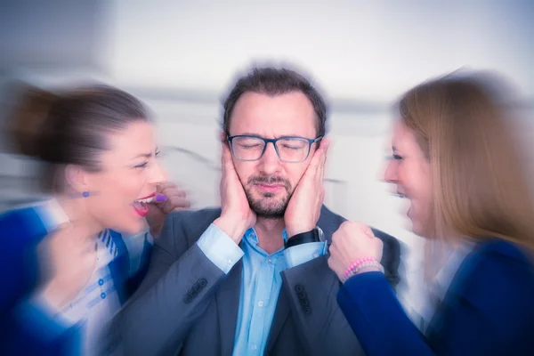 Zakenman bedekt oren met zijn handen. Zakelijke vrouwen schreeuwen tegen hem. — Stockfoto