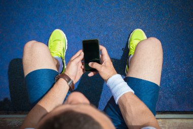Bankta oturan ve smartphone boş ekran ile tutarak koşucu