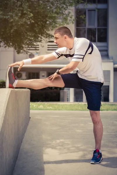 Homem esticando a perna no parque e se preparando para o treino — Fotografia de Stock
