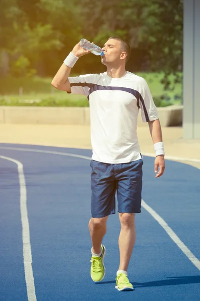 Jogger andando na pista de corrida e água potável da garrafa — Fotografia de Stock