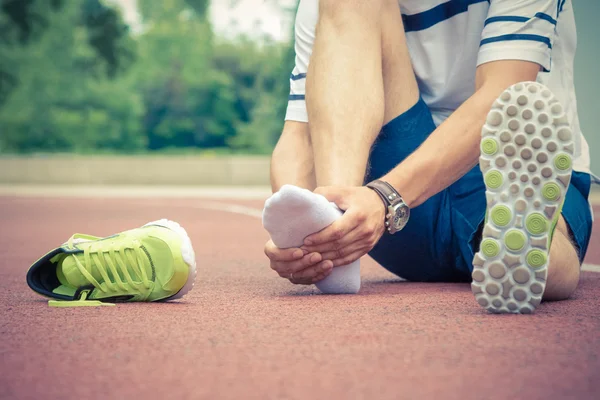 Jogger verificando se seu tornozelo está quebrado ou torcido — Fotografia de Stock