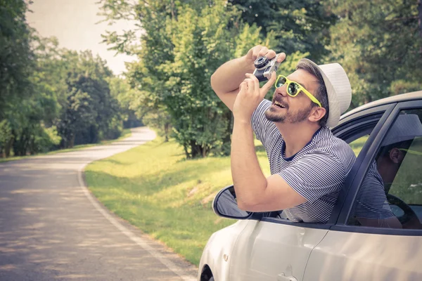 Junge Touristin fotografiert mit Retro-Kamera aus dem Auto — Stockfoto