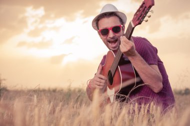 Akustik gitar çalmak ve açık havada şarkı genç adam 