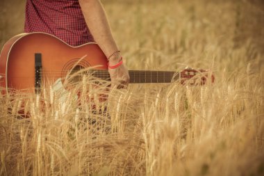 Gitar tutarak ve buğday alanı yürüyen adam 