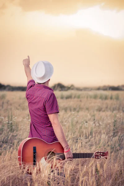 Ung man med akustisk gitarr njuter av solnedgången — Stockfoto