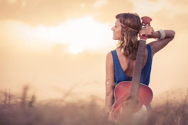 Onun arkasından güneşin tadını akustik gitar ile genç kadın 