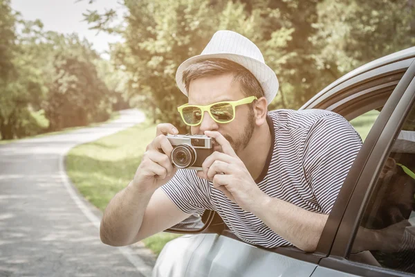 Fiatal turisztikai bevétel fénykép az autó retro fényképezőgép segítségével — Stock Fotó