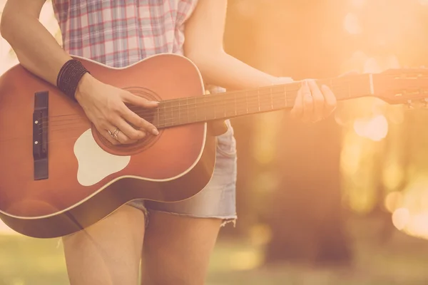 Female playing acoustic guitar outdoors