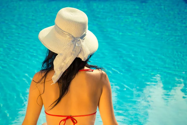 Mujer sentada junto a la piscina — Foto de Stock