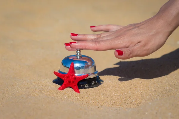 Femmina mano premendo campana hotel sulla spiaggia di sabbia — Foto Stock