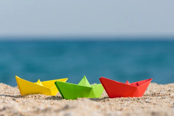 Barche di carta in diversi colori sulla spiaggia — Foto Stock