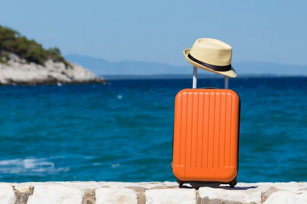 Maleta y sombrero en la playa — Foto de Stock