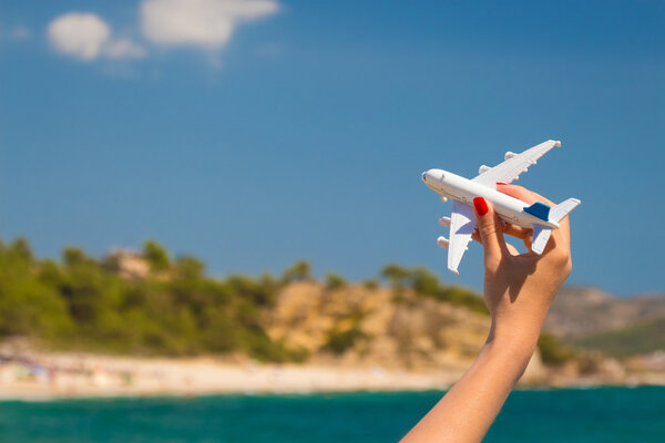 Female hand holding airplane toy at the beach  