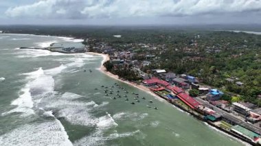 Hikkaduwa sahil şeridinin insansız hava aracı panoraması demirli balıkçı tekneleri, okyanus dalgaları ve Sri Lanka 'da tropikal bir kasaba.