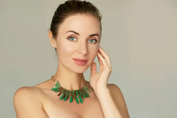 Smiling 30 years old woman portrait.Natural makeup, green necklace. Classic 50mm lens portrait with soft focus, beauty products and procedures concept ilustration.