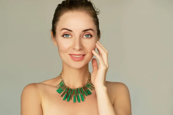 Smiling 30 years old woman portrait.Natural makeup, green necklace. Classic 50mm lens portrait with soft focus, beauty products and procedures concept ilustration.
