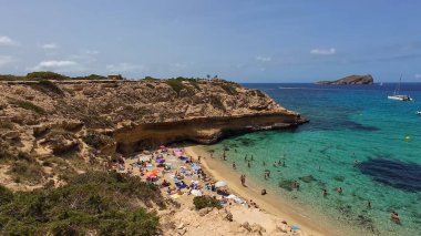 Kumsala gidenler güneşli havanın, berrak suların ve popüler bir adada tatil ve seyahat havasının tadını çıkarıyorlar. 13 Nisan 2023, İbiza Adası, İspanya.