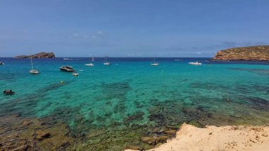 Kumsala gidenler güneşli havanın, berrak suların ve popüler bir adada tatil ve seyahat havasının tadını çıkarıyorlar. 13 Nisan 2023, İbiza Adası, İspanya.