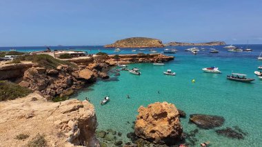 Kumsala gidenler güneşli havanın, berrak suların ve popüler bir adada tatil ve seyahat havasının tadını çıkarıyorlar. 13 Nisan 2023, İbiza Adası, İspanya.