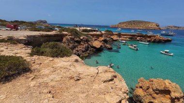 Kumsala gidenler güneşli havanın, berrak suların ve popüler bir adada tatil ve seyahat havasının tadını çıkarıyorlar. 13 Nisan 2023, İbiza Adası, İspanya.