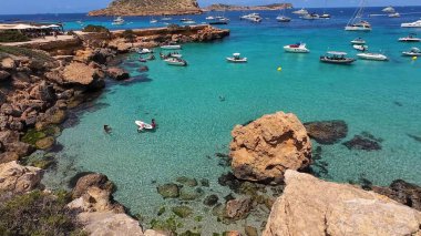 Kumsala gidenler güneşli havanın, berrak suların ve popüler bir adada tatil ve seyahat havasının tadını çıkarıyorlar. 13 Nisan 2023, İbiza Adası, İspanya.