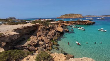 Kumsala gidenler güneşli havanın, berrak suların ve popüler bir adada tatil ve seyahat havasının tadını çıkarıyorlar. 13 Nisan 2023, İbiza Adası, İspanya.