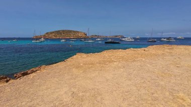 Kumsala gidenler güneşli havanın, berrak suların ve popüler bir adada tatil ve seyahat havasının tadını çıkarıyorlar. 13 Nisan 2023, İbiza Adası, İspanya.