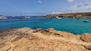 Kumsala gidenler güneşli havanın, berrak suların ve popüler bir adada tatil ve seyahat havasının tadını çıkarıyorlar. 13 Nisan 2023, İbiza Adası, İspanya.