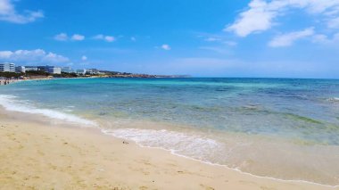 Canlı sahil titreşimleri, altın kumlar, manzara ve güneşli gökyüzü, tatil için mükemmel bir yer, turne, seyahat, rahatlama ve plaj aktiviteleri. Limanaki Plajı, Ayia Napa, Kıbrıs - 26 Temmuz 2023.
