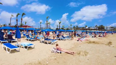 Canlı sahil titreşimleri, altın kumlar, manzara ve güneşli gökyüzü, tatil için mükemmel bir yer, turne, seyahat, rahatlama ve plaj aktiviteleri. Limanaki Plajı, Ayia Napa, Kıbrıs - 26 Temmuz 2023.