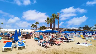 Canlı sahil titreşimleri, altın kumlar, manzara ve güneşli gökyüzü, tatil için mükemmel bir yer, turne, seyahat, rahatlama ve plaj aktiviteleri. Limanaki Plajı, Ayia Napa, Kıbrıs - 26 Temmuz 2023.