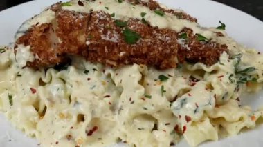 Zengin beyaz soslu ve yumuşak tavuklu kremalı tavuk ve İtalyan restoranı usulü sıcak servis edilen alfredo makarna. Makarna menüleri, İtalyan mutfak promosyonları, yemek pazarlaması ve kremalı makarna tabaklarının sergilendiği ticari stok görüntüleri için mükemmel..