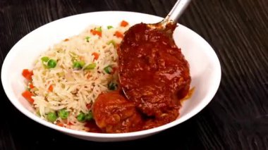 Körili tavuk, baharatlı pirinçle servis edilir, soslu ve aromatik pirinçle harmanlanır. Bu yemek Hint mutfağı menüleri, restoran promosyonları, konforlu yemek görselleri, yemek servisi içeriği ve körili yemeklerin yer aldığı ticari stok görüntülerine uyuyor..