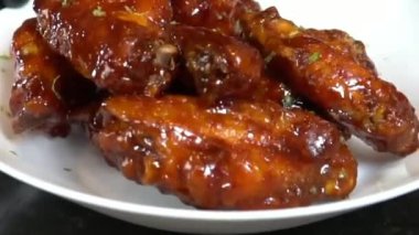 Bal jöleli tavuk kanatları yumuşak ve tatlı bal jölesiyle kaplanana kadar pişirilir, sıcak ve parlak bir kaplama ile servis edilir. Restoran menüleri, parti tabakları, sıradan yemek görselleri ve tatlı kanatları ön plana çıkaran ticari stok görüntüleri için ideal..