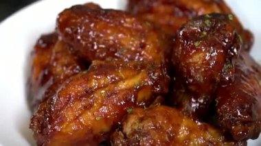 Yapışkan jöleli ve sulu etle hazırlanmış tatlı ballı tavuk kanatları. Restoran tarzı sunumda sıcak servis ediliyor. Menü sergileri, parti atıştırmalıkları, yemek pazarlama ve aromalı tavuk kanatları içeren ticari stok görüntüleri için mükemmel..