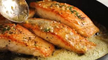 Lezzetli sarımsaklı somon balığı aromatik tereyağı sosuyla pişirilir, sıcak ve zarif bir sunumla servis edilir. Restoran menüleri, gurme deniz ürünleri promosyonları, sağlıklı yemek görselleri ve somon tabaklarının sergilendiği ticari stok görüntüleri için ideal..